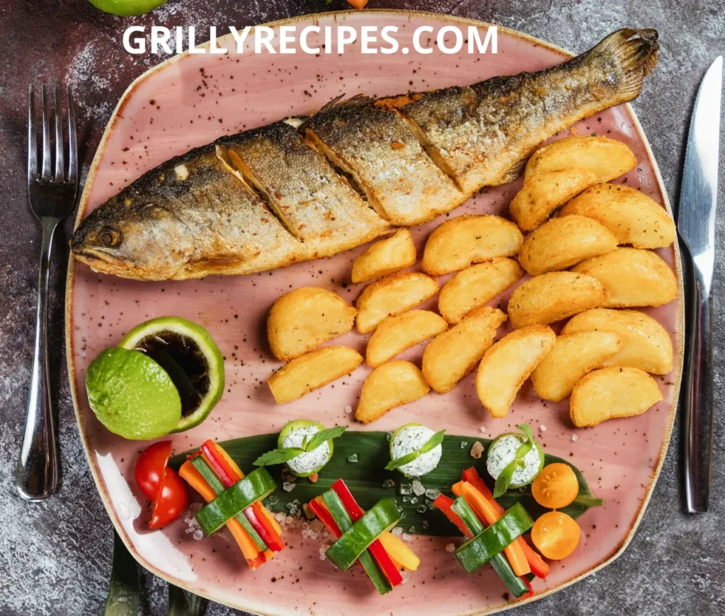 Grilled whole fish served with crispy potato wedges and fresh vegetable garnishes on a rustic pink plate.