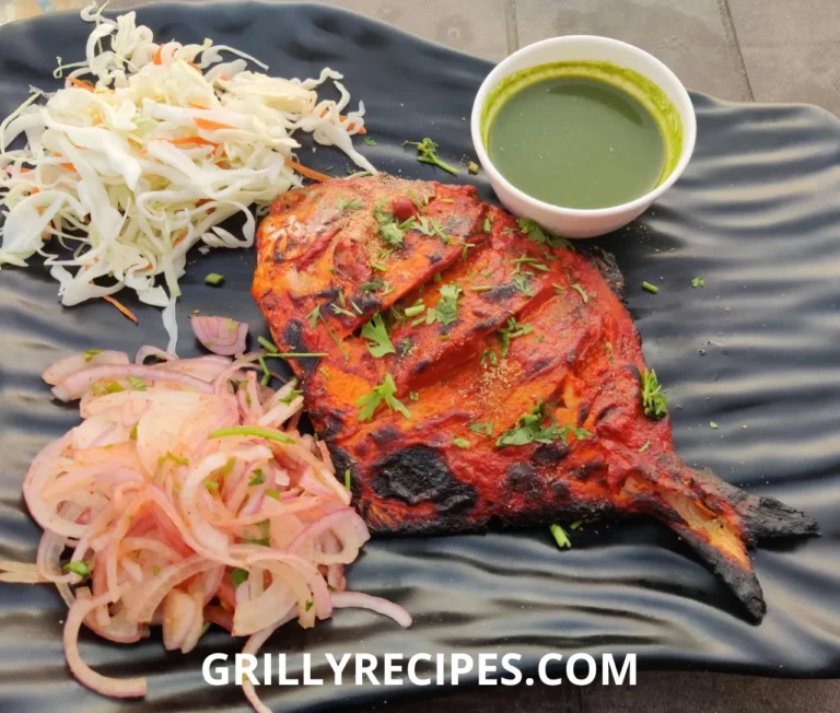Spicy grilled fish with a smoky char, served with fresh onion salad, cabbage slaw, and green chutney on a black plate.