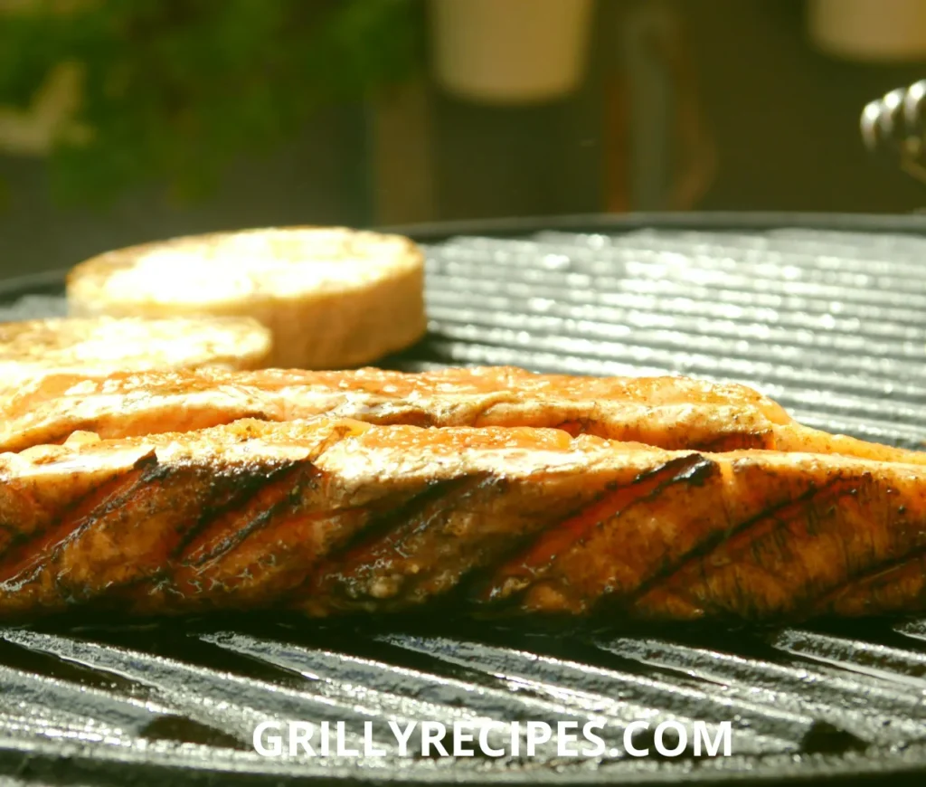 Perfectly grilled fish fillets with fresh herbs and lemon slices on a grill.

