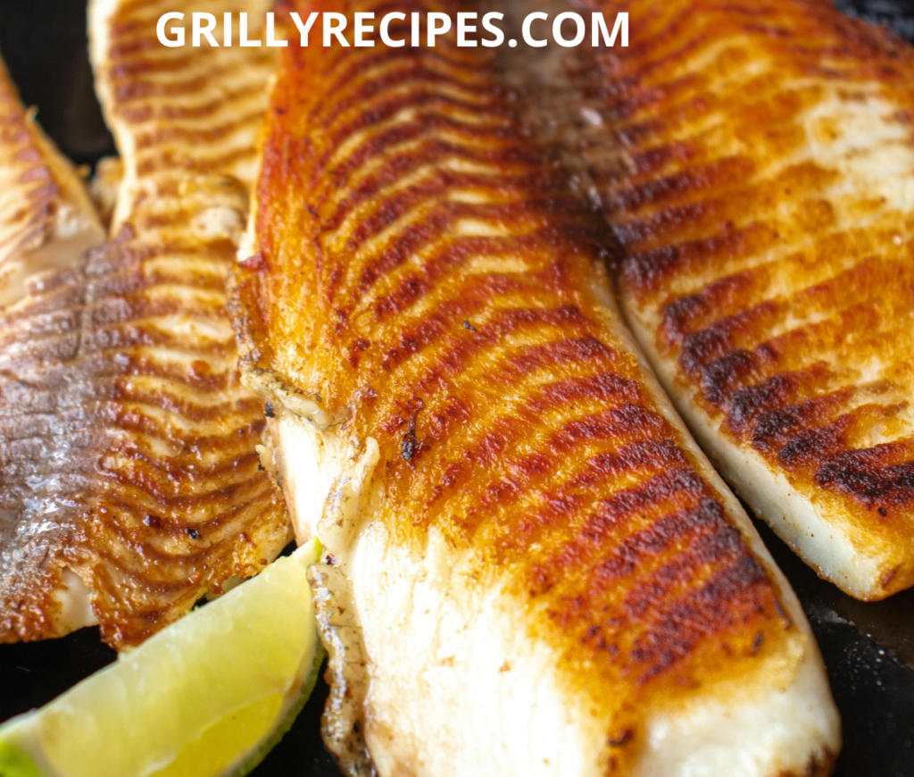 Freshly grilled branzino fillet garnished with lemon slices and herbs.

