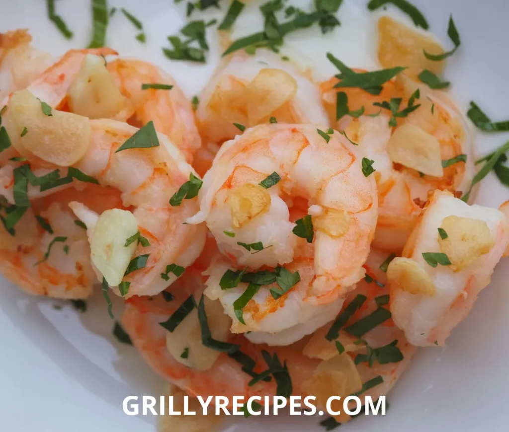 Succulent shrimp in a rich garlic butter sauce, garnished with fresh parsley and a lemon wedge on a white plate, showcasing a flavorful shrimp garlic butter recipe.