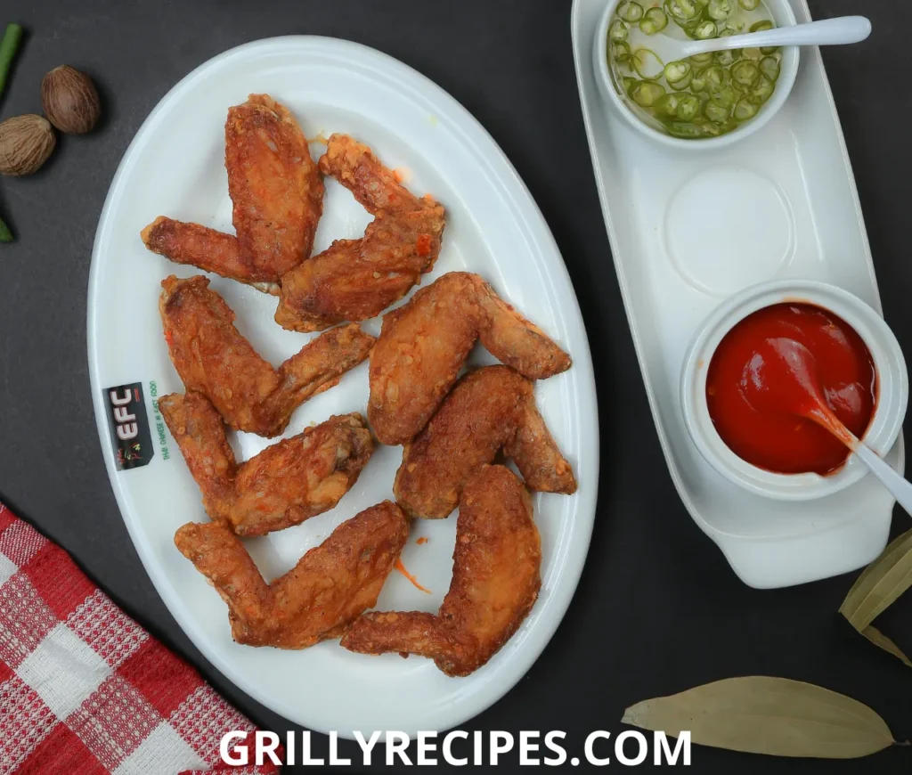 Juicy grilled chicken wings with a golden-brown char, served with dipping sauce on a wooden plate.