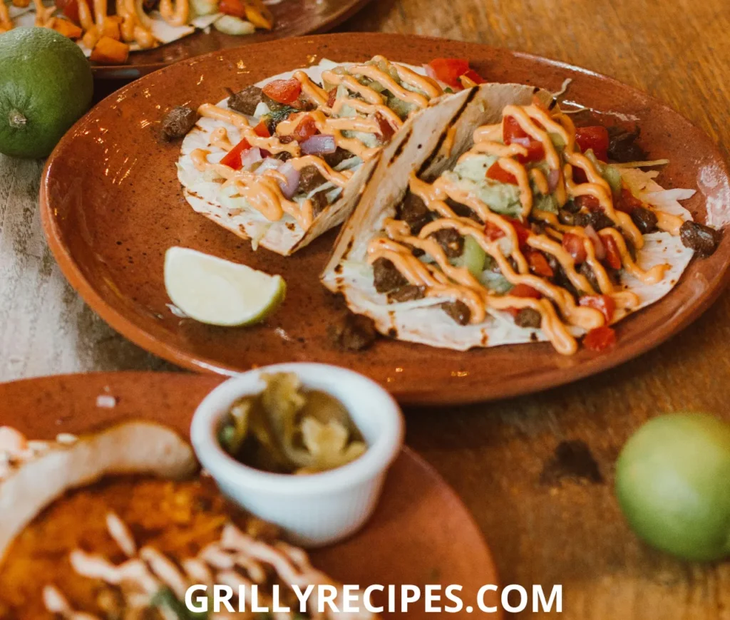 Grilled beef tacos with fresh toppings and a drizzle of creamy sauce.