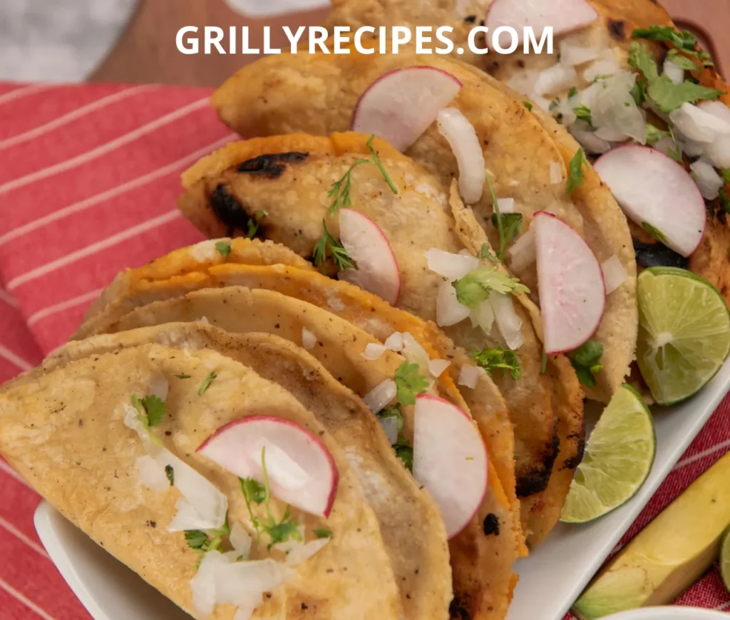 Plate of grilled fish tacos garnished with fresh radish, onion, and lime wedges.