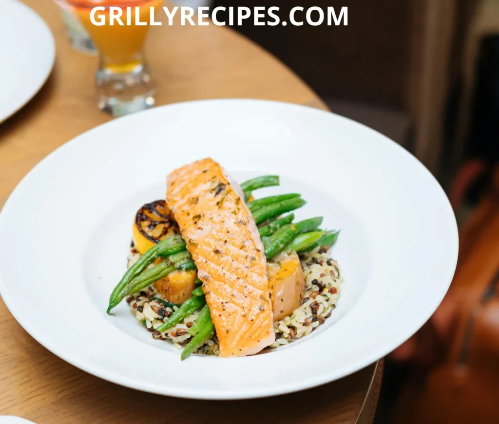 Grilled salmon fillet served with green beans, roasted vegetables, and quinoa on a white plate.