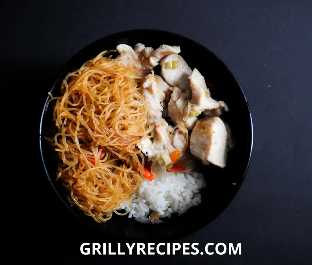 A comforting bowl of chicken long rice with tender chicken, glass noodles, and green onions in a flavorful broth.


