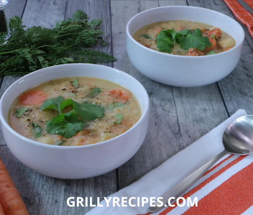 A bowl of homemade lentil soup with carrots and fresh cilantro, served on a rustic wooden table.