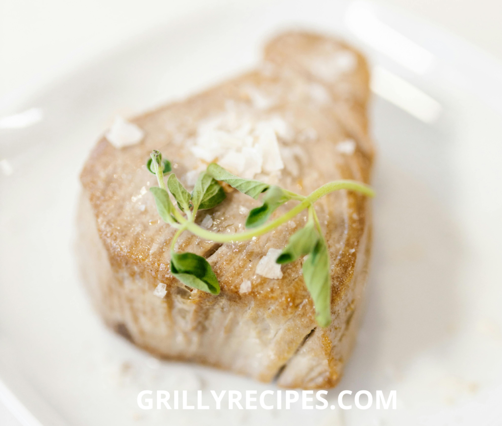 A seared Grilled Tuna Steak Recipe with microgreens and flaky sea salt.