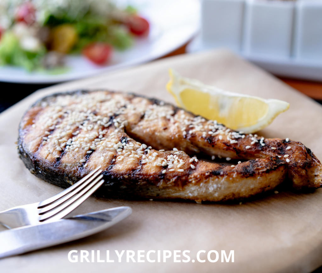 Grilled Tuna Steak Recipe with sesame seeds, served with a lemon wedge on parchment paper.