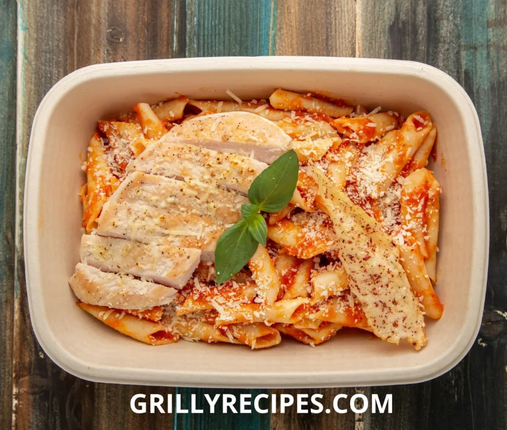 A bowl of creamy chicken pasta garnished with fresh herbs and parmesan cheese.